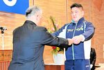 亀井副知事（左）から表彰状を受け取る相撲成年男子のソソルフー選手＝鳥取市の白兎会館