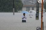 　大雨の影響で冠水した道路を歩く人＝２０２３年７月、福岡県久留米市