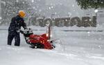 　積雪したＪＲ鳥取駅前で除雪作業をする人＝２４日午後