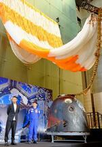 　ＺＯＺＯ創業者の前沢友作さん（左から２人目）が地球帰還時に使った宇宙船の帰還モジュールと大型パラシュート＝２７日午前、東京・日本橋