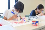 見本のデザインロゴやオリジナルイラストなどを描く参加者＝１７日、鳥取市東町の県立博物館
