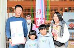 坂田会長（左から２人目）から記念品を贈られ、喜ぶ小野さん家族＝２２日、香美町香住区余部の道の駅あまるべ