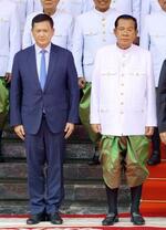 　３日、カンボジアの首都プノンペンで記念撮影に応じるフン・セン氏（右）とフン・マネット首相（共同）