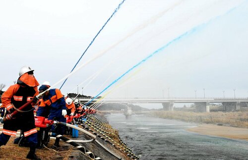 天神川に向かって一斉放水する消防団員ら＝５日、倉吉市の飛天夢広場