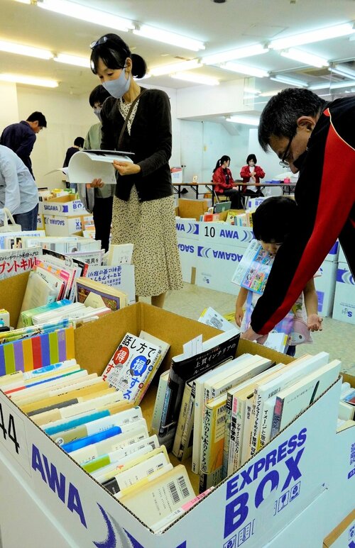 古本市で好みの本を品定めする家族連れ