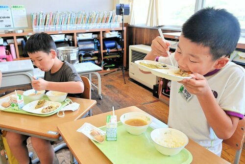旬の地元食材を使った給食を口いっぱいにほおばる児童ら＝４日、琴浦町の赤碕小