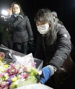 　スキーバス転落事故現場近くにある慰霊碑を訪れ、献花する女性たち。２人とも当時大学生の息子が事故で負傷した＝１５日午前１時５２分、長野県軽井沢町