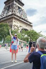 　エッフェル塔前で、フランス国旗を羽織った姿で写真に納まる女性＝３日、パリ（共同）