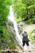 涼しげに水が流れ落ちる猿尾滝にカメラを向ける観光客＝３日、香美町村岡区日影