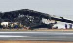 　羽田空港の滑走路で炎上し、焼け焦げた日航機を調べる警視庁の捜査員ら＝３日午後３時４０分