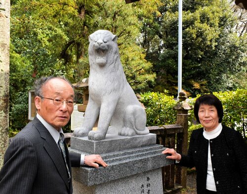 参道の両脇に設置されたライオン型のこま犬と発起人の福田さん（左）、川口さん＝９日、鳥取市馬場の倉田八幡宮