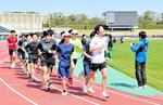 「エネルギアランニングスクール」で岡本直己選手を先頭に長距離走を行う中高生ら＝３０日、鳥取市布勢のヤマタスポーツパーク陸上競技場