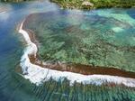 　チョープーの海岸から数百メートル先の沖合まで広がる岩礁とサンゴ礁。うねりがぶつかり大波が立つ＝フランス領ポリネシア・タヒチ＝ドローンから・共同、２０２３年１１月
