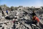 　２２日、パレスチナ自治区ガザ南部ラファで、イスラエル軍の空爆を受けた場所を調べる人々（ロイター＝共同）
