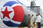 　新たに建造された「戦術核攻撃潜水艦」のそばに立つ北朝鮮の金正恩朝鮮労働党総書記（左から２人目）＝６日（朝鮮中央通信＝共同）