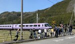 沿線で紫色の特急やくもを撮影する鉄道写真愛好家＝３０日、鳥取県日野町下榎