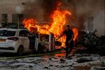 　７日、パレスチナ自治区ガザからのロケット弾攻撃で燃え上がる炎と逃げる男性＝イスラエル中部アシュケロン（ロイター＝共同）