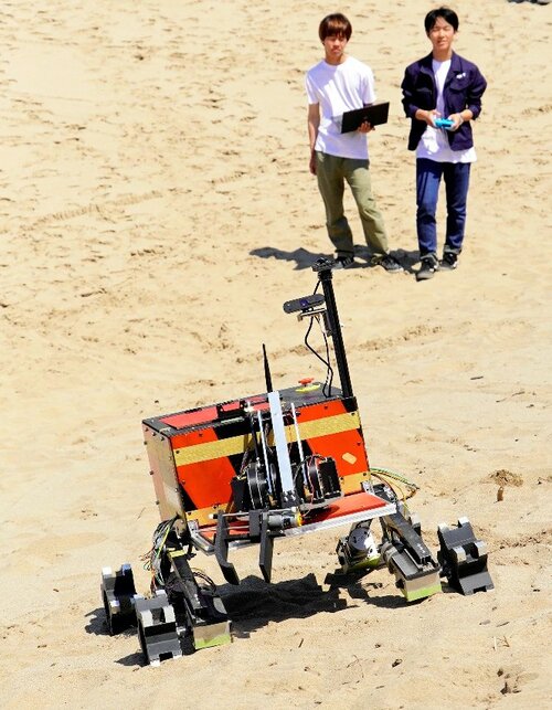 砂地の斜面で地球外探査ローバーの走行を試験するメンバー＝鳥取市浜坂のルナテラス