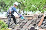 屋根に上がり瓦を清掃するメンバー＝８日、倉吉市仲ノ町の飛龍閣