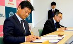 協定書に署名する木村社長（左）と深沢市長＝９日、鳥取市役所