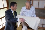 伊達市長（左）からお祝いの品として贈られた膝かけを手にする景山さん＝１８日、境港市中野町