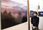 　杉浦さんが撮影した富士山の写真の前で、撮影に応じるボランティア団体の代表＝群馬県草津町