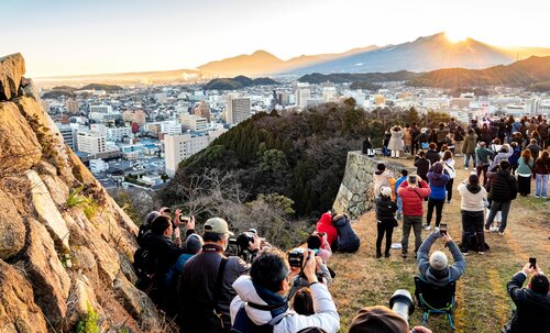 大山山頂付近に輝く朝日を堪能する登城者ら＝１８日、鳥取県米子市久米町の米子城跡天守台