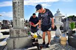 墓に水をかけたり、花を生けたりする親子＝１２日、琴浦町赤碕の花見潟墓地