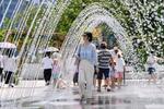 　３日、韓国・ソウル中心部にある広場で、噴水の中を歩く人（共同）
