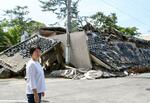 　能登半島地震で倒壊した重蔵神社の前に立つ禰宜の能門亜由子さん＝６月、石川県輪島市