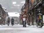 　雪の舞う金沢市の観光名所「ひがし茶屋街」を歩く人たち＝２２日午後