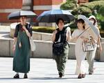 　ＪＲ東京駅前を日傘を差して歩く人たち＝２６日午後