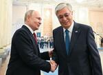 　９日、カザフスタンの首都アスタナでトカエフ大統領（右）と握手するロシアのプーチン大統領（タス＝共同）
