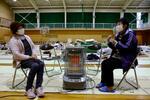 　避難所となっている小学校の体育館で暖を取る人たち＝９日午前、石川県七尾市