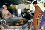 　客と話すチャッパル・カバーブの料理人リアーカト・カーンさん（左）＝２０２４年６月６日、パキスタン・イスラマバード（共同）
