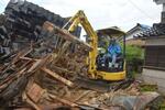 ショベルカーで崩れた家を道の端に寄せる藤野さん＝６月３日、石川県珠洲市