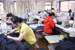 　「エイ・アイプランニング」の縫製工場で働く従業員ら＝１７日、東京都江東区