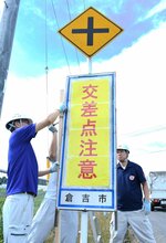  交差点の存在を伝える注意看板を設置する市職員ら＝３日、倉吉市国府 