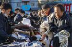 　無料で配られた冬物衣類を受け取る労働者ら（右側）＝１３日午後、大阪市西成区