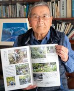 １８年間の活動を記録した記念誌を手にする吉岡会長