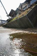 　地震による液状化で外構が傾いた石川県内灘町の家屋。マンホールからは水があふれていた＝２日午後