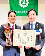 川上会長から賞状とトロフィーを受け取り笑顔を見せる古海さん（左）