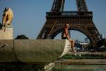 　パリのエッフェル塔前で日光浴をする男性＝９月７日（ＡＰ＝共同）