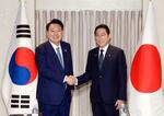 　１０日、ワシントンで韓国の尹錫悦大統領（左）と握手する岸田首相（聯合＝共同）