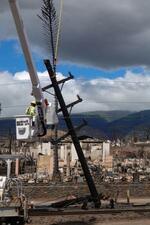 　山火事の被害を受けた米ハワイ・マウイ島ラハイナで、電線を補修する作業員＝１５日（ロイター＝共同）