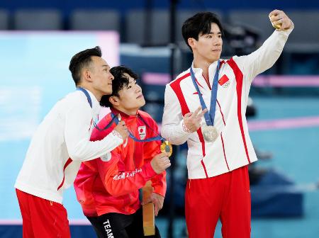 　体操男子個人総合で優勝し、表彰台で中国選手と記念撮影する岡慎之助（中央）＝７月、パリ（共同）