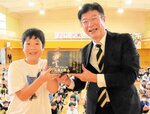 森本局長（右）から「決定版　ゲゲゲの鬼太郎」の全１４巻を受け取る島谷さん＝３日、境港市湊町の境小