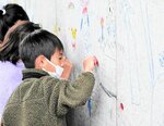 チョークを使って橋脚にカラフルな絵を描く子どもたち＝５日、倉吉市石塚の国道３１３号高架橋建設現場