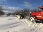 　大雪に見舞われたウクライナ南部ミコライウ州で、車を引き出そうとする救助隊員ら＝２７日（非常事態庁提供・ロイター＝共同）