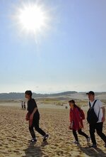 強い日差しが照り付ける中、薄着で散策を楽しむ観光客＝２日午後２時１６分、鳥取市の鳥取砂丘